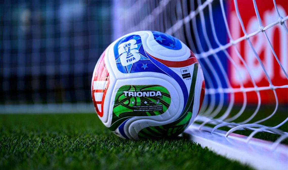 The FIFA World Cup 2026 official Trionda Pro match ball resting against the goal net on the pitch